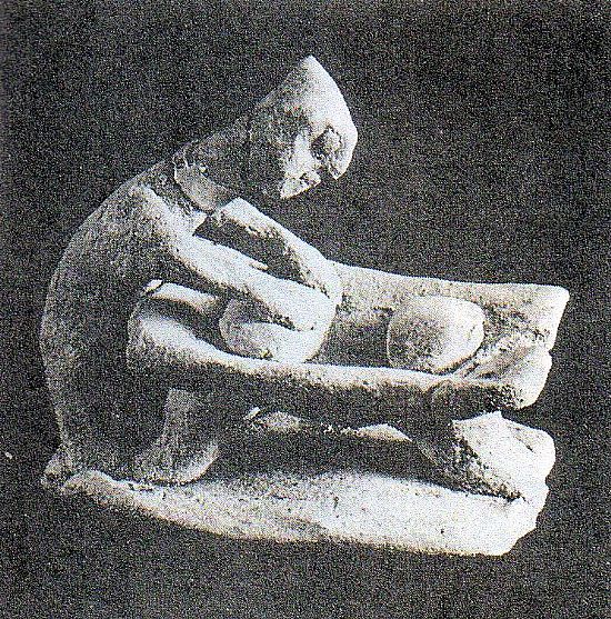 a clay figurine kneading dough in a trough