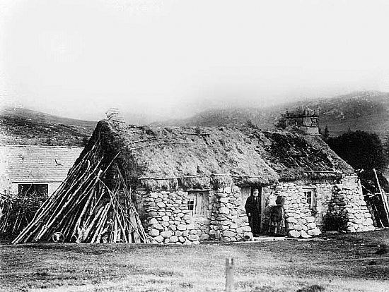 Black and white photo of old thatched house.