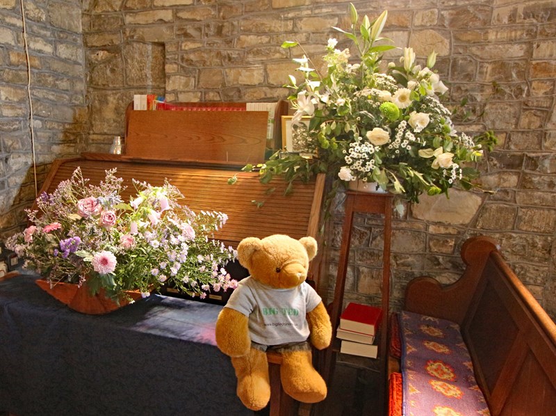 Big Ted beside flower arrangements