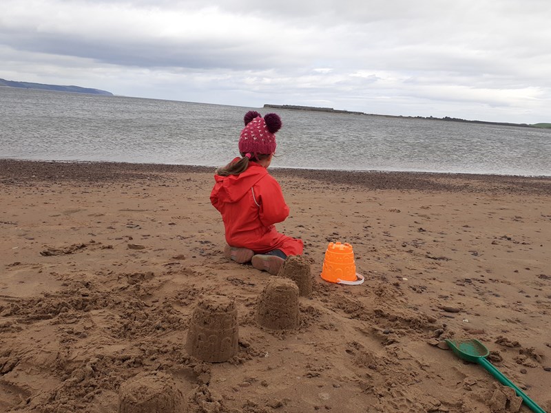 young girl making sandcastle on the beach