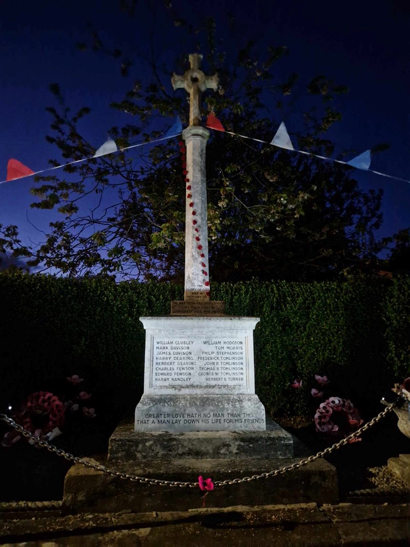 North Frodingham War Memorial at night with decorations and potlights 