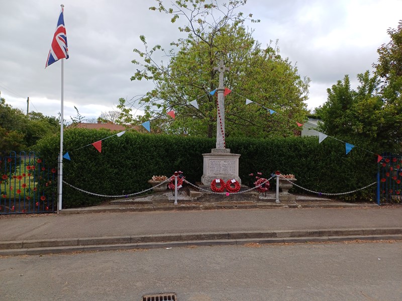 War Memorial decorated with flags and nearby flagpole flying a flag