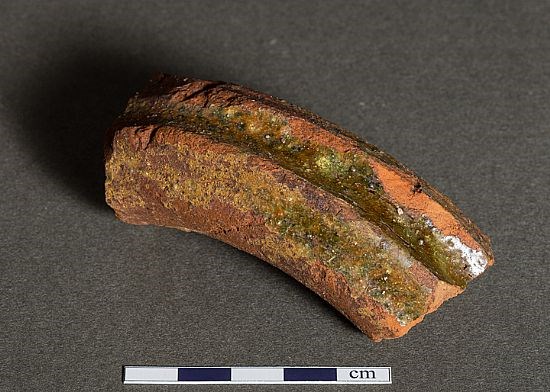 Handle of a medieval redware jug with green glaze