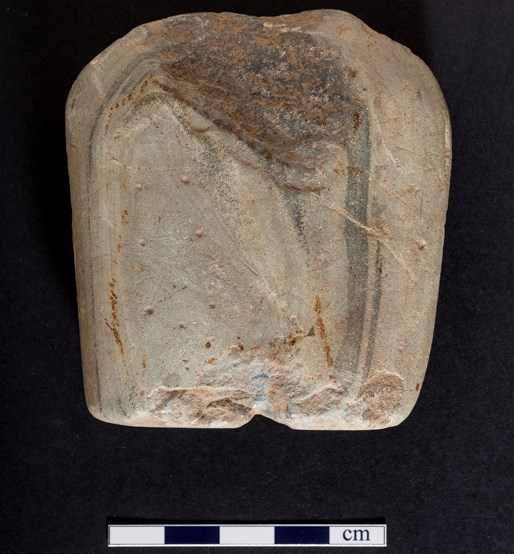 Part of a Neolithic stone axe showing a number of small depressions on the stone face