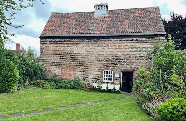 A red brick building from the exterior showing the glover or opening on the roof where the doves would have entered