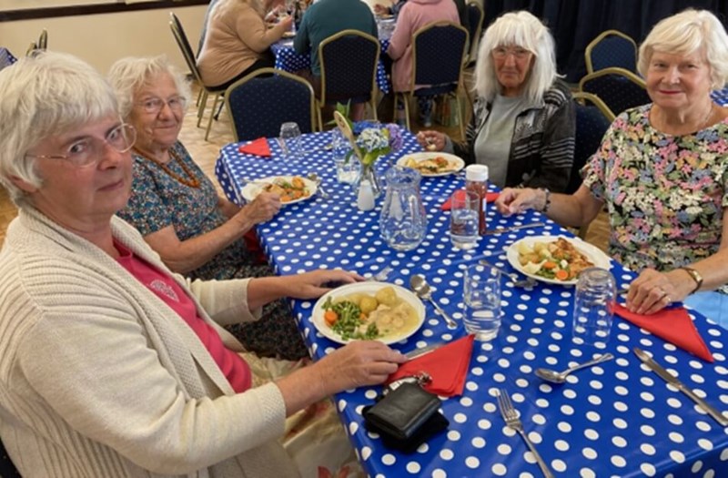 People sitting round a table with food and looking at the camera