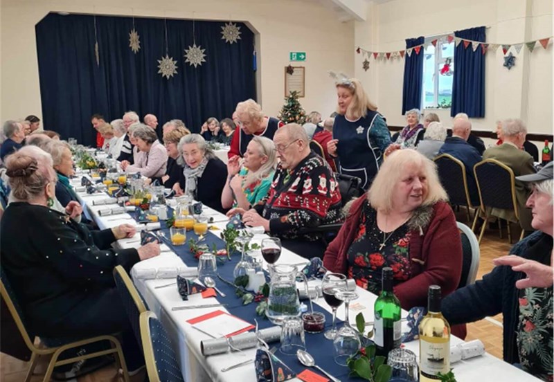 People sitting at long table eating Christmas lunch