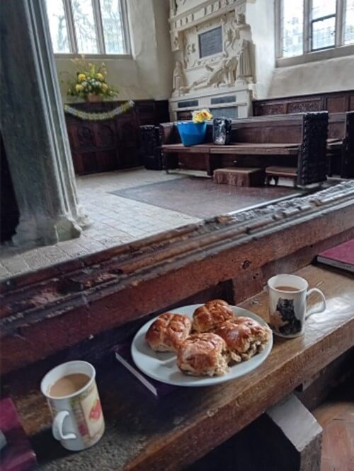 Inside the church with buns and drinks on a table in the foreground and flowers in the distance