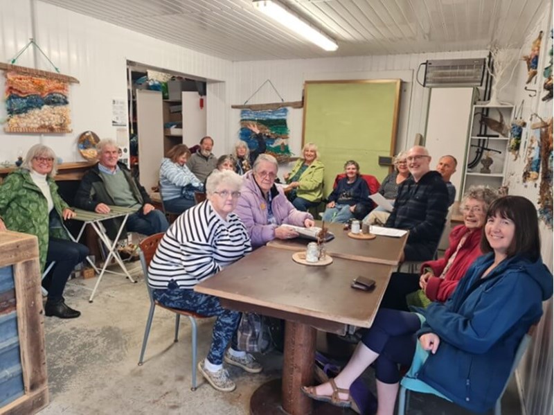 People sitting at tables, looking at the camera and smiling