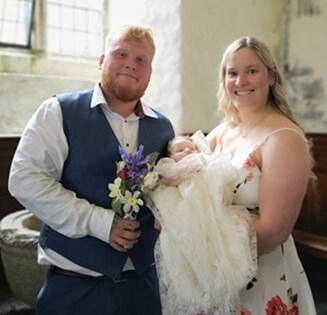Couple holding their baby and smiling at the camera