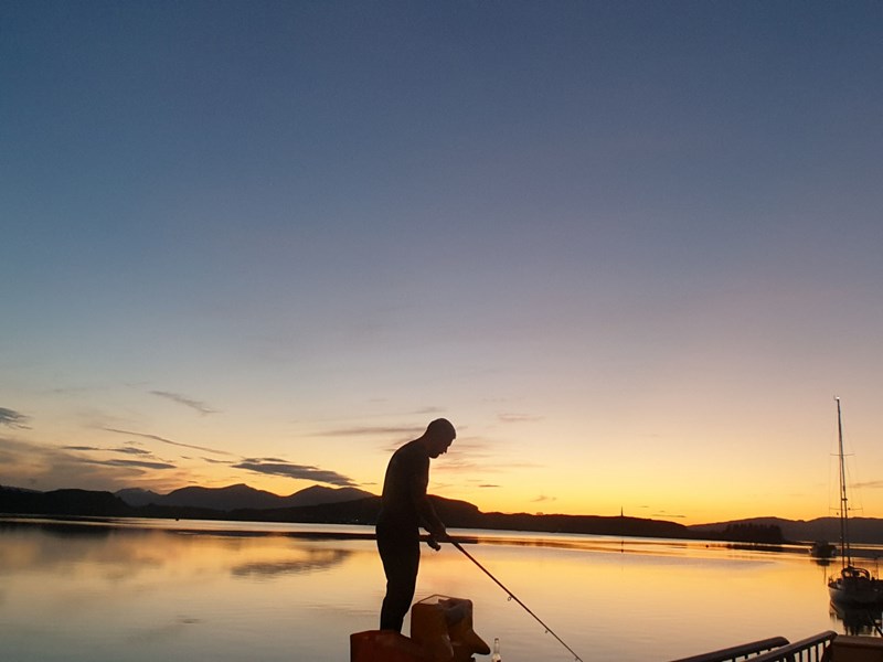 Fisherman in the sunset on Oban's North Pier