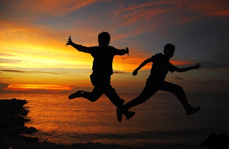 Kids jumping with the sunset in the background
