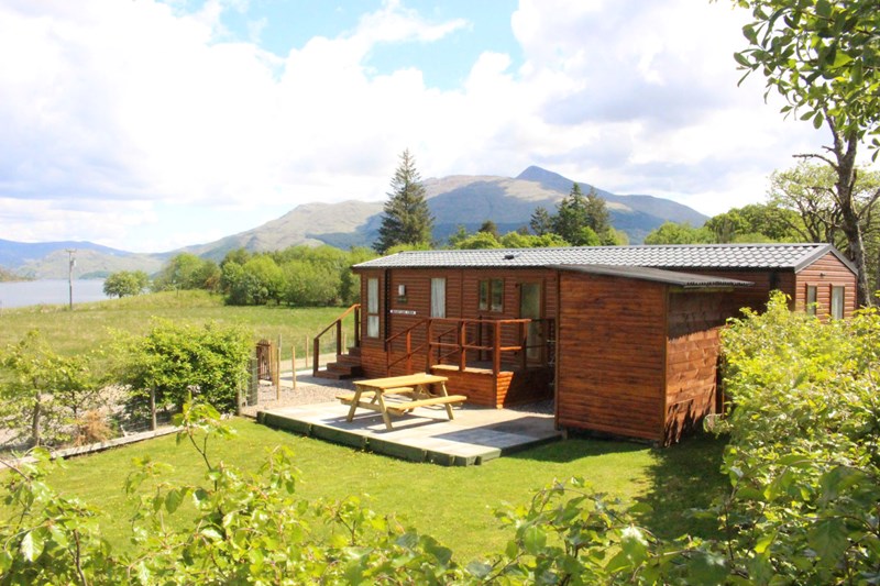 Mountain View from the side, showing side garden, patio and furniture, parking, utility shed, blue skies and Ben Cruachan in the background